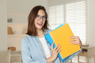 Photo of Smiling teenage girl with notepads at home