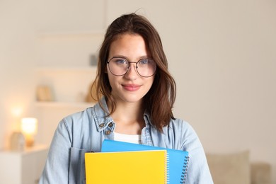 Photo of Portrait of beautiful teenage girl with notepads at home