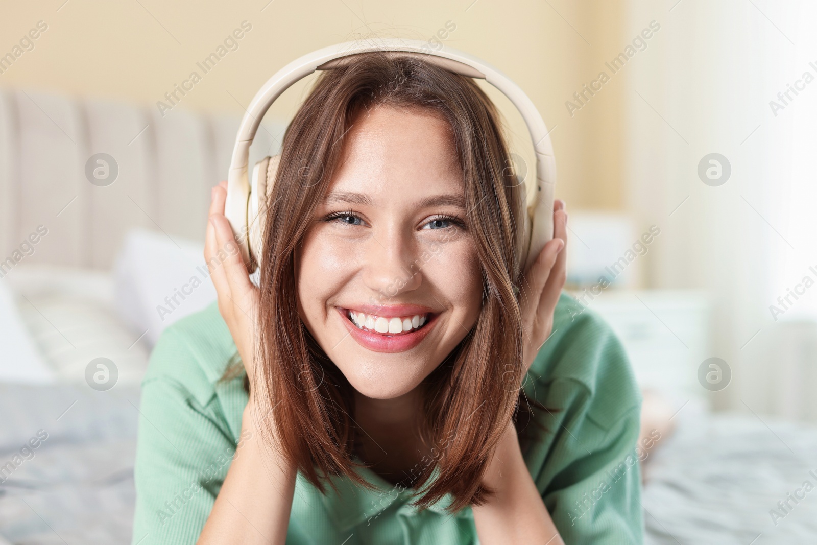Portrait of smiling teenage girl in headphones listening to music at home Photo of Portrait of smiling teenage girl in headphones listening to music at home