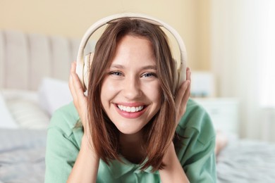 Photo of Portrait of smiling teenage girl in headphones listening to music at home