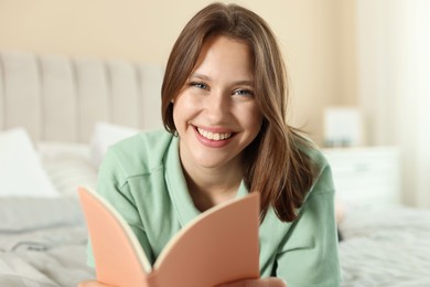 Photo of Portrait of smiling teenage girl with book at home