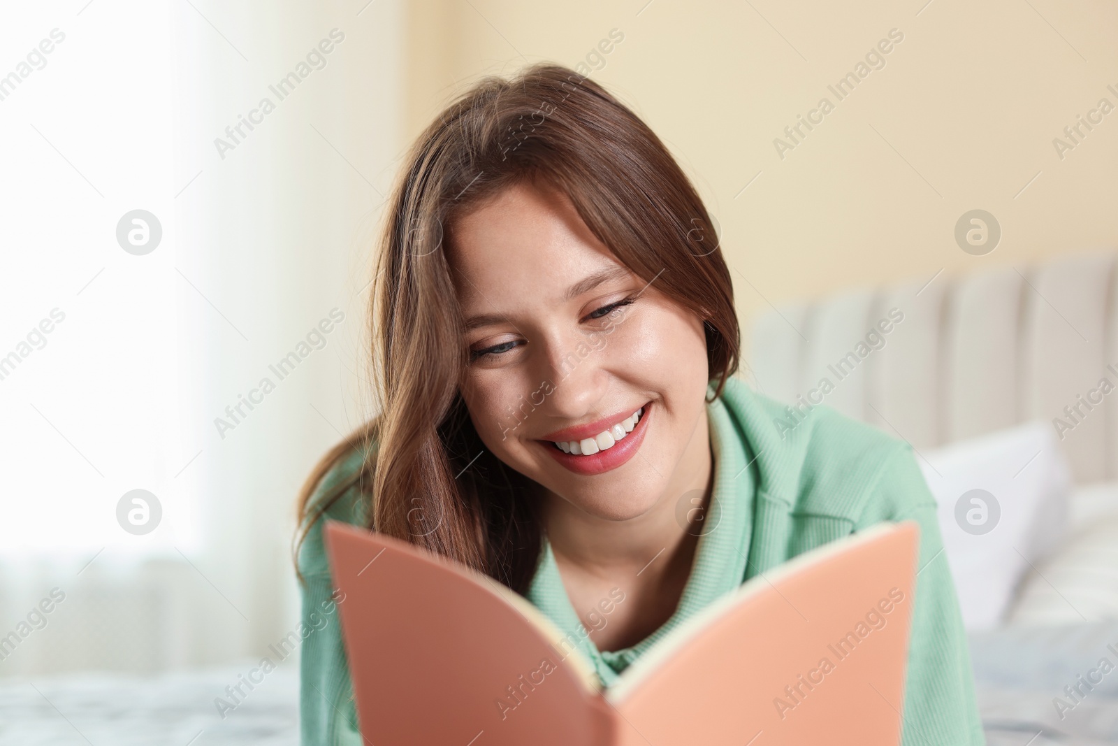 Smiling teenage girl with book at home Photo of Smiling teenage girl with book at home