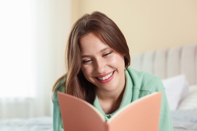 Photo of Smiling teenage girl with book at home