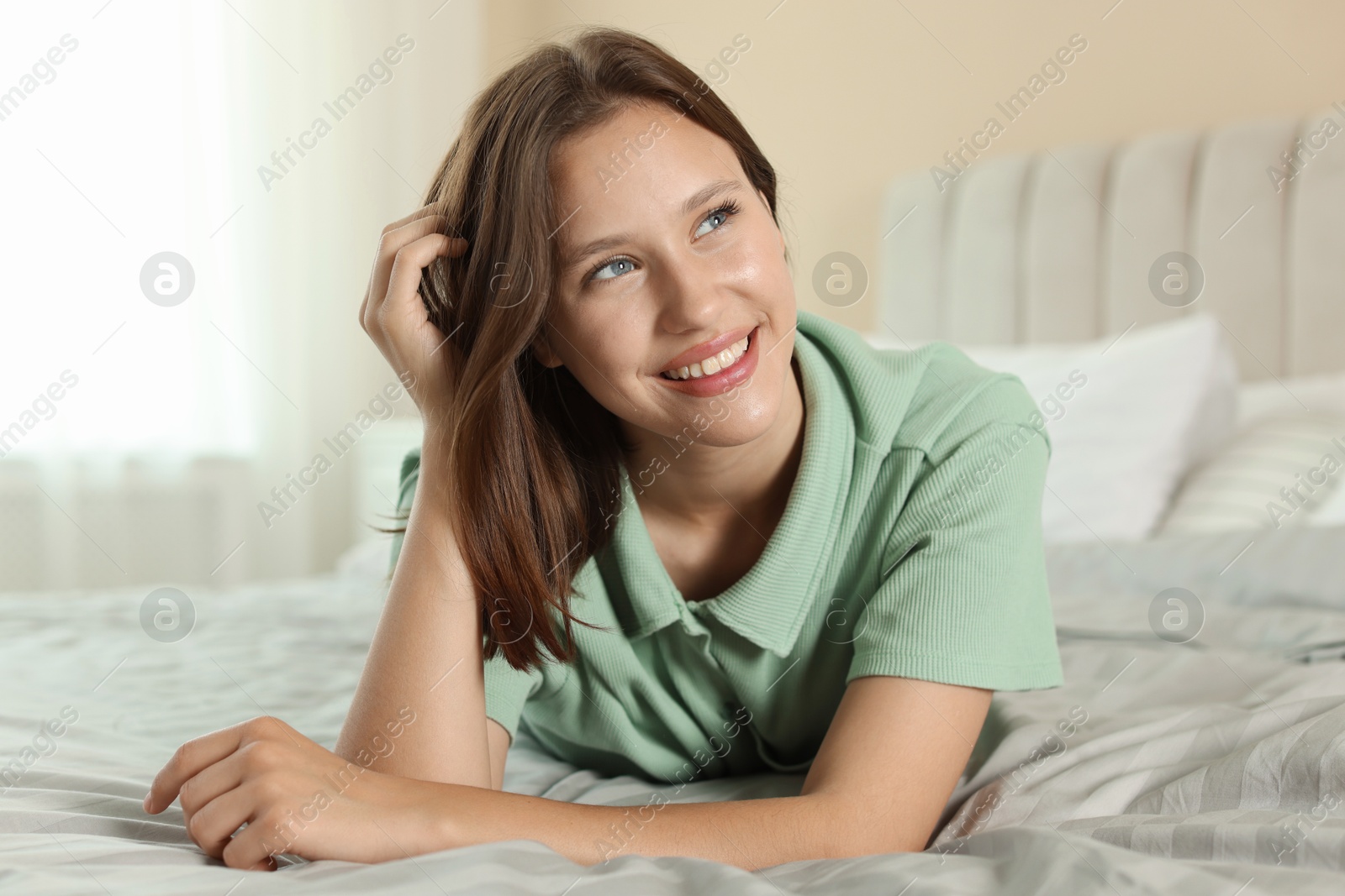 Portrait of smiling teenage girl on bed at home Photo of Portrait of smiling teenage girl on bed at home