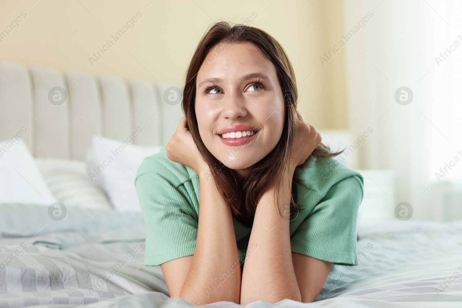 Portrait of smiling teenage girl on bed at home Photo of Portrait of smiling teenage girl on bed at home