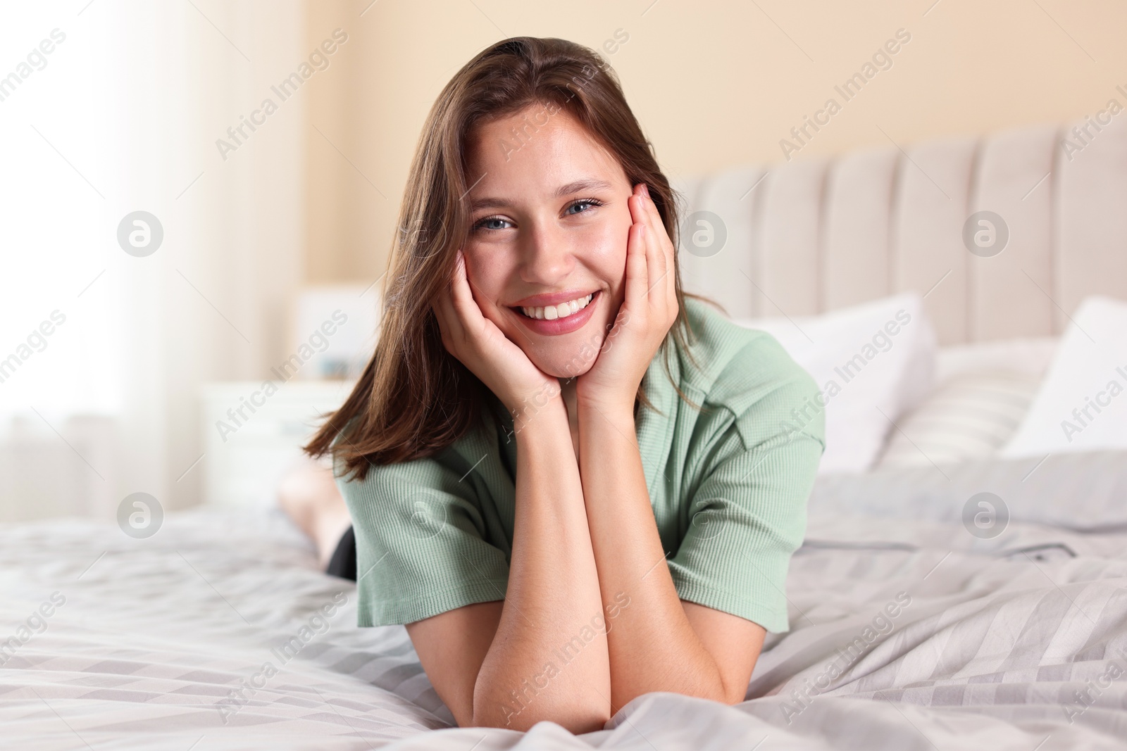 Portrait of smiling teenage girl on bed at home Photo of Portrait of smiling teenage girl on bed at home