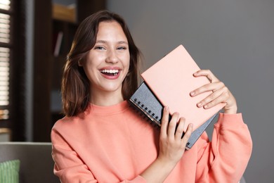Photo of Smiling teenage girl with notebooks at home