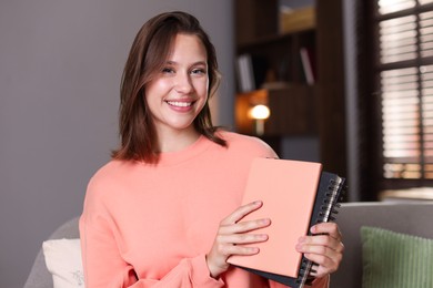 Photo of Smiling teenage girl with notebooks at home