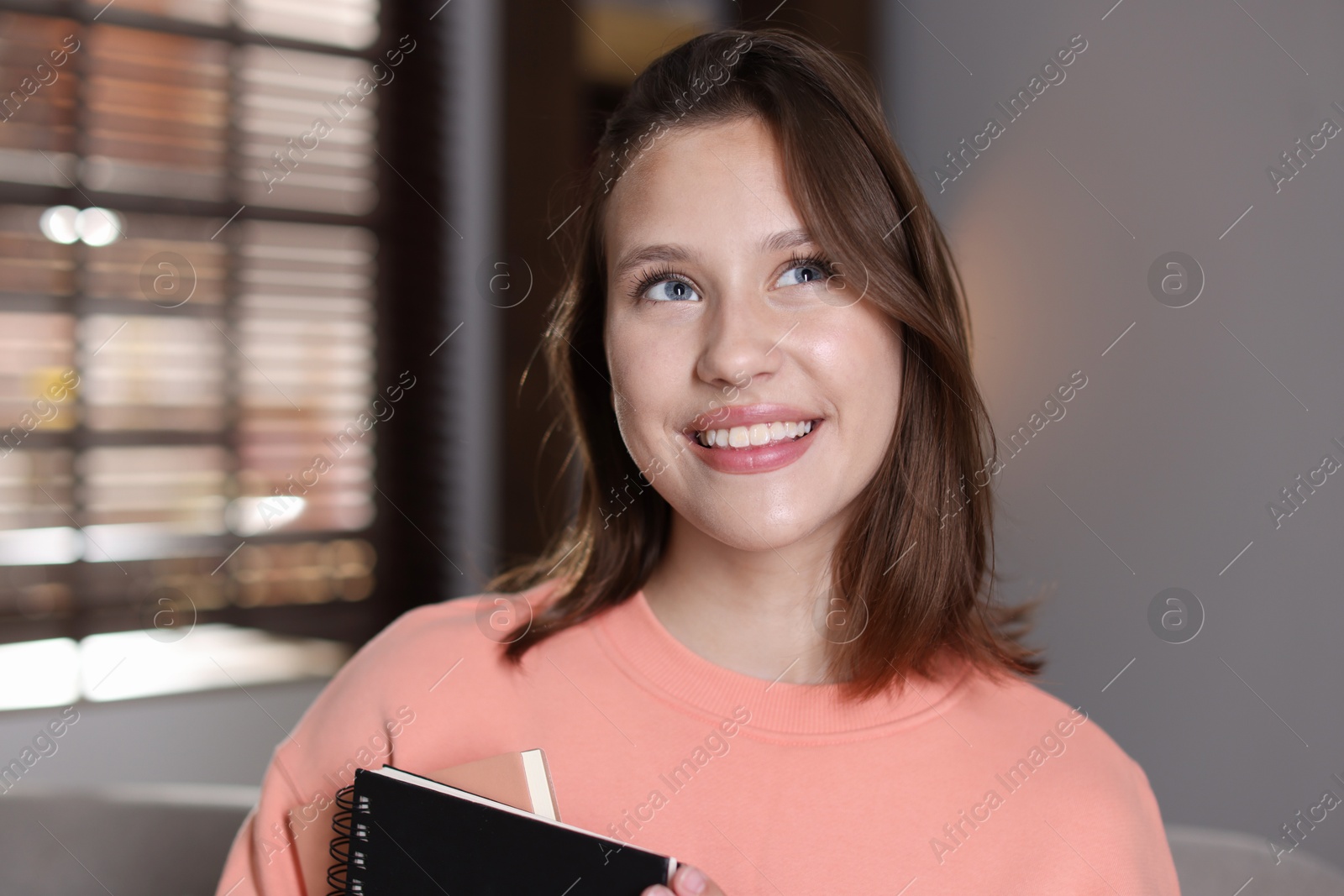 Smiling teenage girl with notebooks at home Photo of Smiling teenage girl with notebooks at home