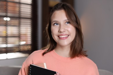 Photo of Smiling teenage girl with notebooks at home
