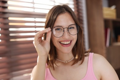 Photo of Portrait of smiling teenage girl in glasses at home