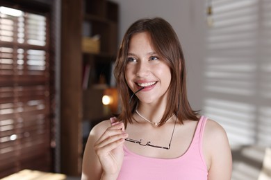 Photo of Smiling teenage girl with glasses at home