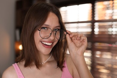 Photo of Portrait of smiling teenage girl in glasses at home