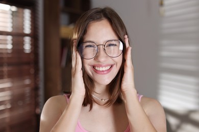 Photo of Portrait of smiling teenage girl in glasses at home