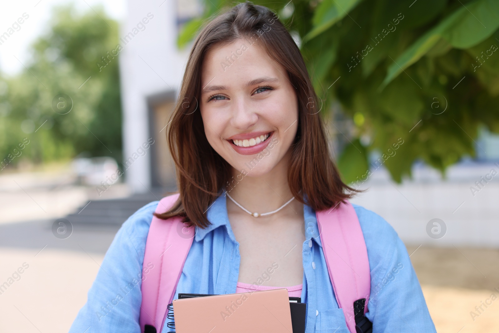 Portrait of smiling teenage girl with notebooks outdoors Photo of Portrait of smiling teenage girl with notebooks outdoors