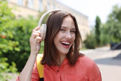 Photo of Smiling teenage girl in headphones listening to music outdoors
