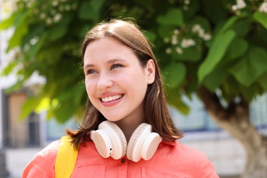 Photo of Smiling teenage girl with headphones on city street