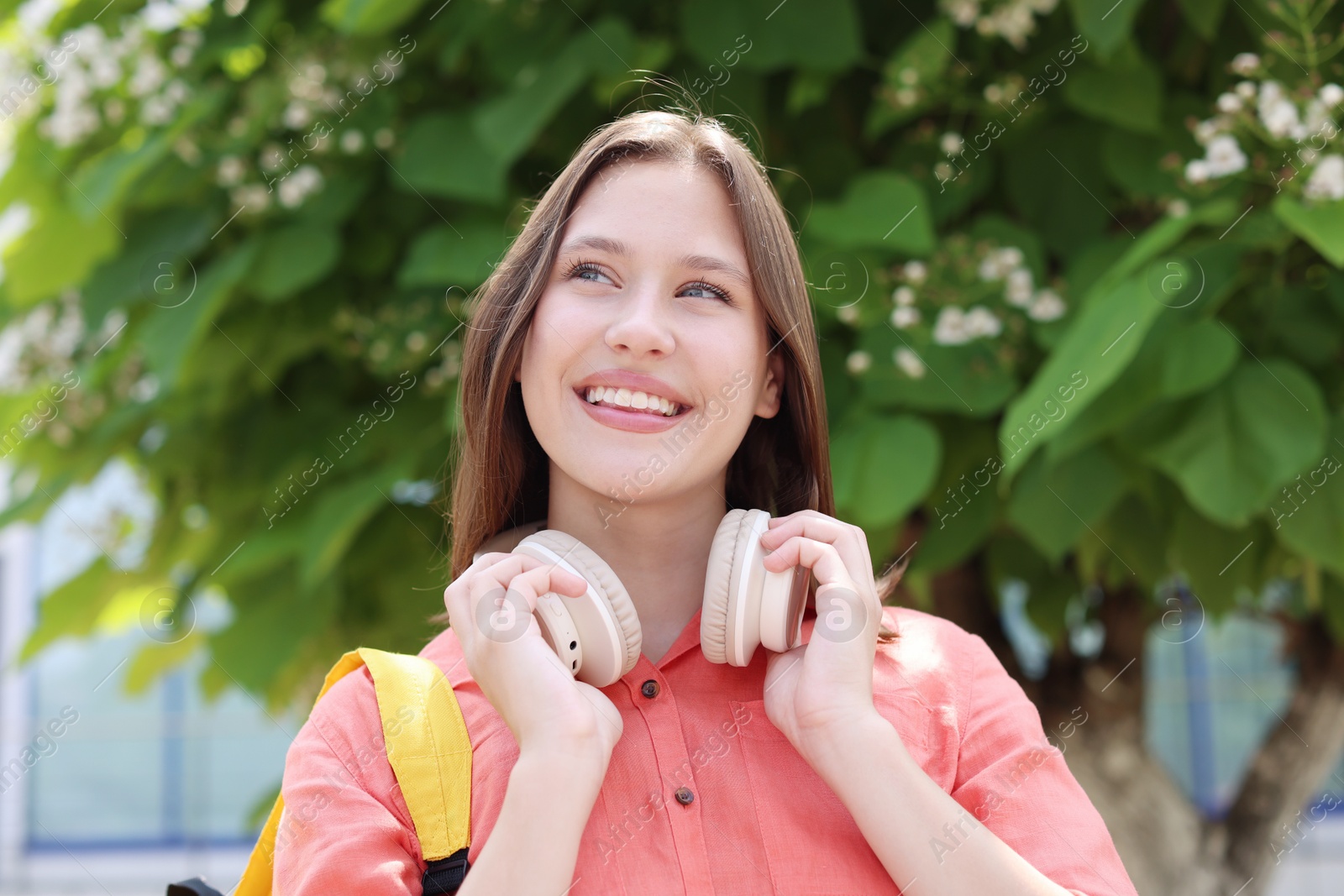 Smiling teenage girl with headphones on city street Photo of Smiling teenage girl with headphones on city street