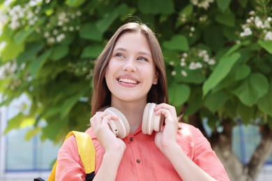 Photo of Smiling teenage girl with headphones on city street