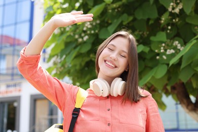 Photo of Smiling teenage girl with headphones on city street