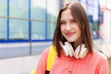 Photo of Portrait of beautiful teenage girl with headphones outdoors. Space for text