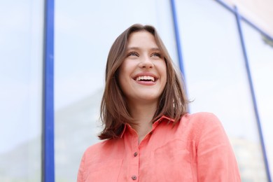 Photo of Smiling teenage girl near building outdoors, low angle view