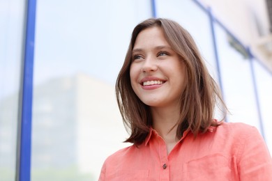 Photo of Smiling teenage girl near building outdoors, low angle view