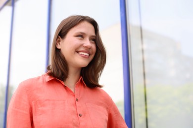 Photo of Smiling teenage girl near building outdoors, low angle view