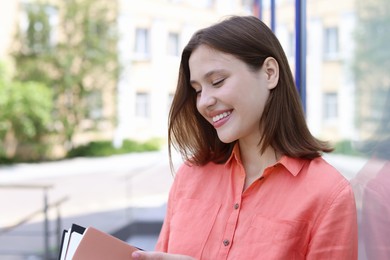 Photo of Smiling teenage girl with notepads on city street