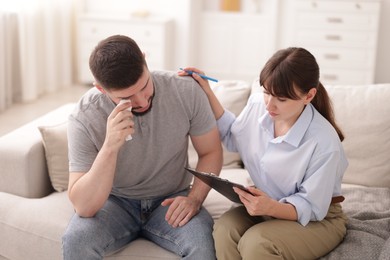 Photo of Psychologist supporting patient during therapy session on sofa in office