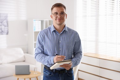 Photo of Portrait of psychologist in glasses with notepad and pen in office
