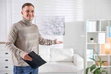 Photo of Smiling psychologist with clipboard inviting to sofa in office