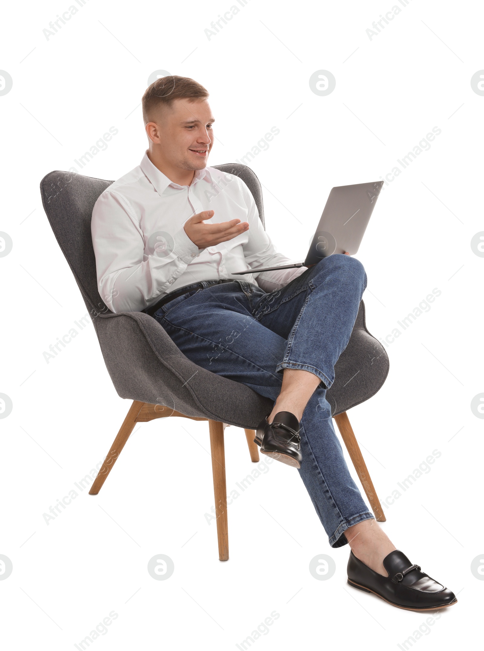 Smiling psychologist during online session by laptop sitting on armchair against white background Photo of Smiling psychologist during online session by laptop sitting on armchair against white background
