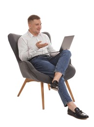 Photo of Smiling psychologist during online session by laptop sitting on armchair against white background
