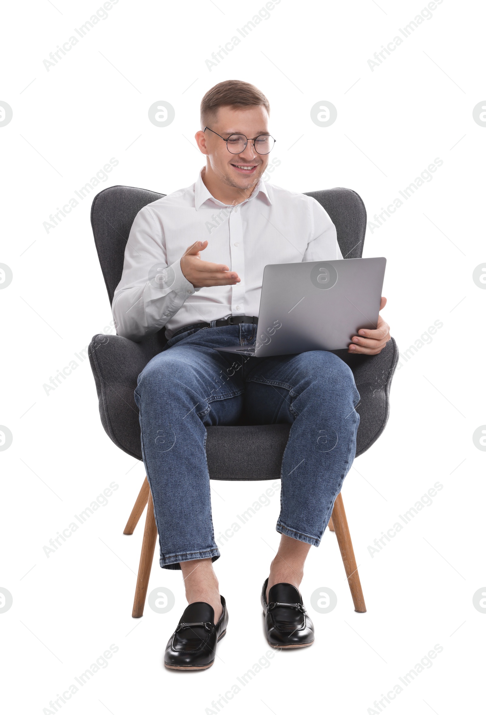 Photo of Smiling psychologist in glasses during online session by laptop sitting on armchair against white background