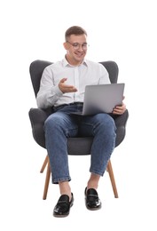 Photo of Smiling psychologist in glasses during online session by laptop sitting on armchair against white background