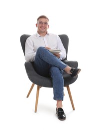 Photo of Smiling psychologist in glasses with notepad sitting on armchair against white background