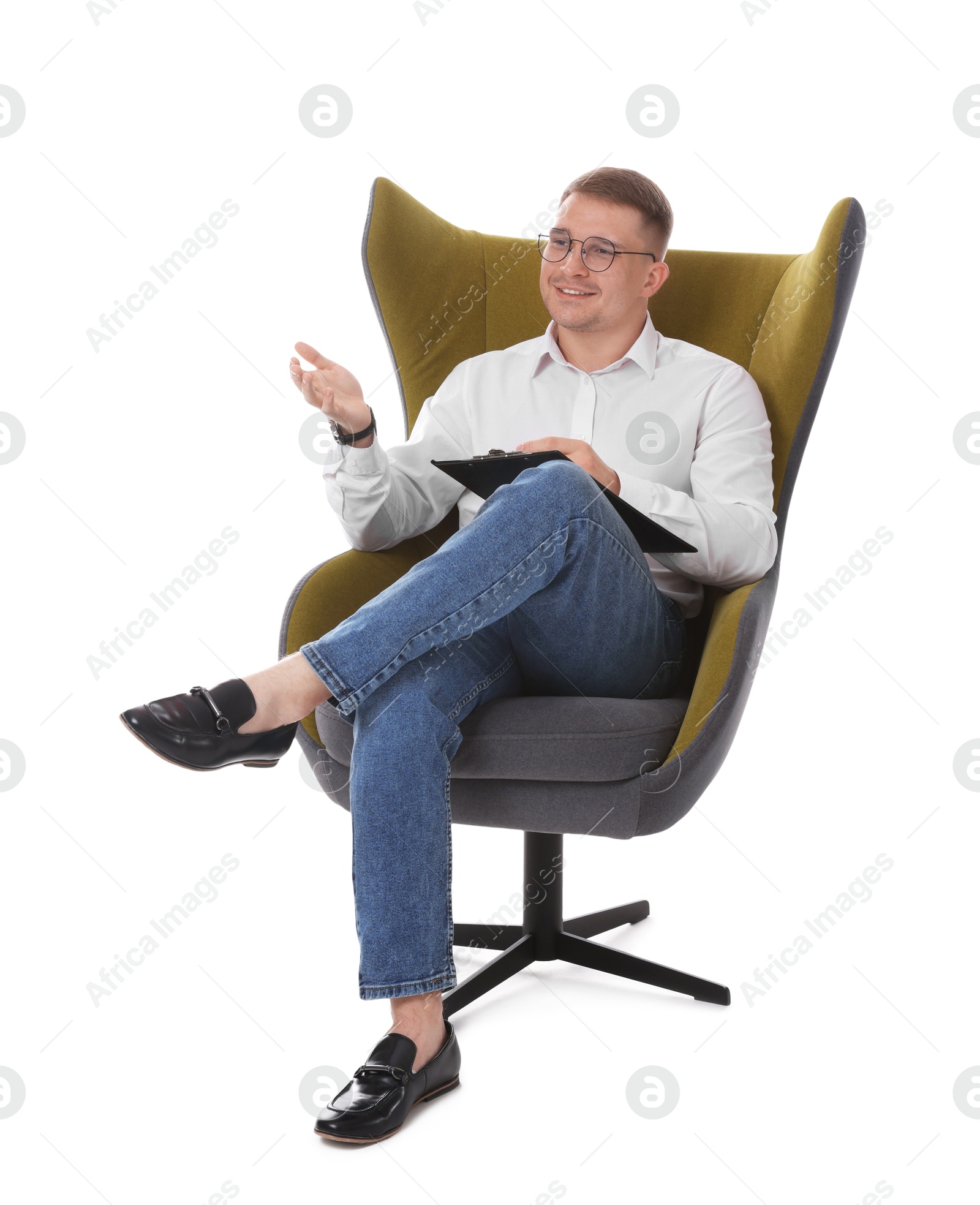 Photo of Smiling psychologist in glasses with clipboard sitting on armchair against white background