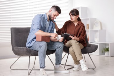 Photo of Psychologist supporting patient during therapy session in office