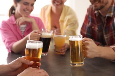 Photo of Friends with glasses of beer at grey table indoors, selective focus