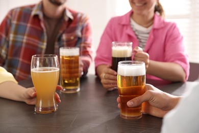 Photo of Friends with glasses of beer at grey table indoors, selective focus