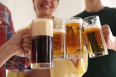 Photo of Friends clinking glass mugs of beer indoors, low angle view