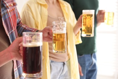 Photo of Friends with glass mugs of beer indoors, closeup