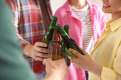 Photo of Friends clinking bottles of beer indoors, closeup