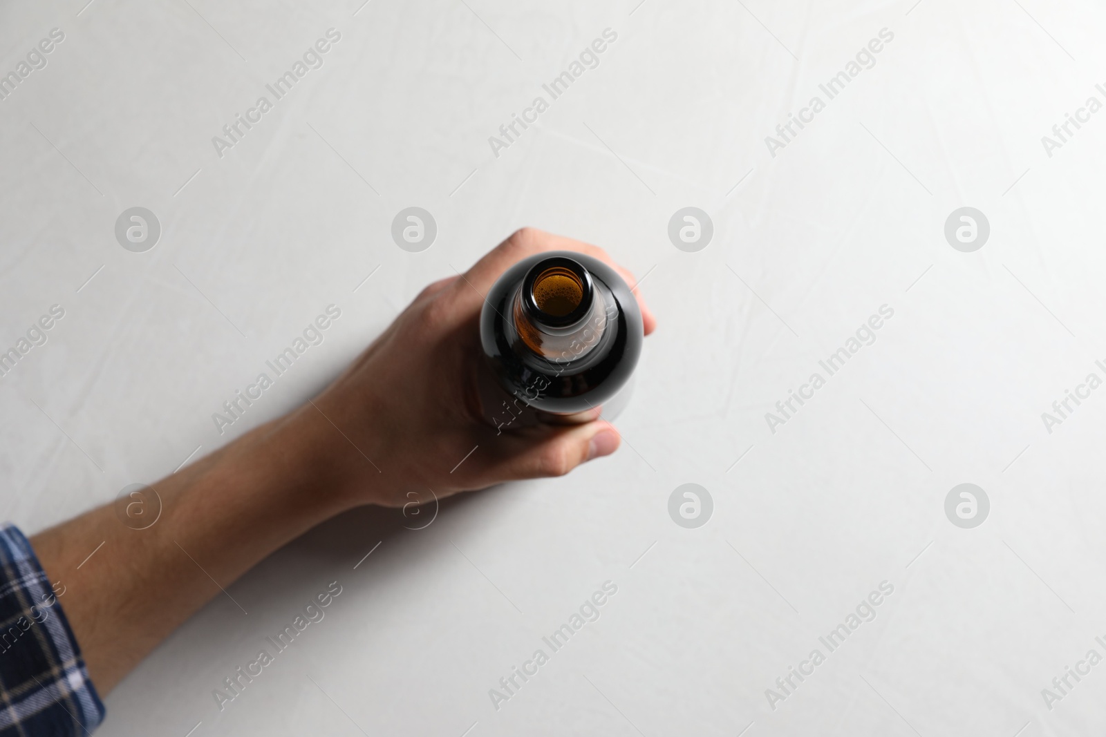 Photo of Man with bottle of beer at white table, top view