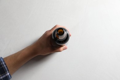 Photo of Man with bottle of beer at white table, top view