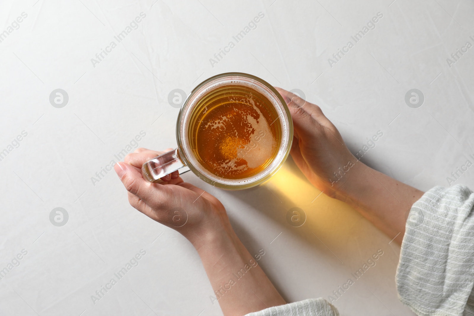 Photo of Woman with glass mug of beer at white table, top view