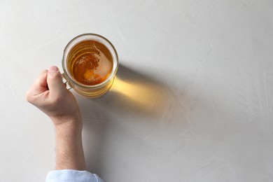 Photo of Man with glass mug of beer at white table, top view. Space for text