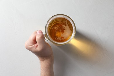 Photo of Man with glass mug of beer at white table, top view