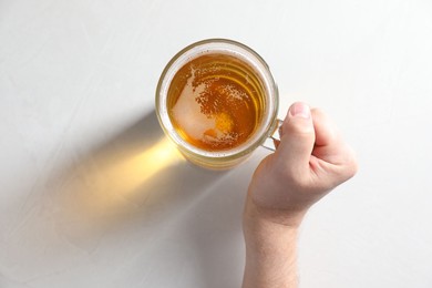 Photo of Man with glass mug of beer at white table, top view